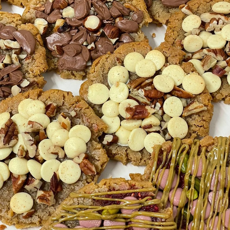 Cookies Gourmands : Chocolat, Noix et Rocky Road Assortiment gourmand de cookies épais, décorés de pépites de chocolat blanc, noix de pécan, chocolat au lait et d'un cookie style rocky road.