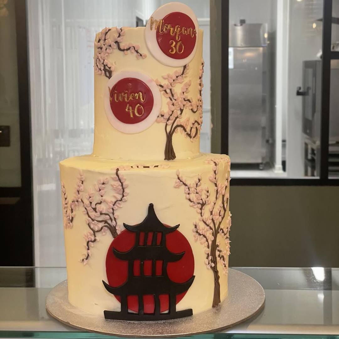 Gâteau deux étages style japonais avec fleurs de cerisier. Orné des textes "Morgan 30" et "Vivien 40". Pagode noire sur disque rouge.